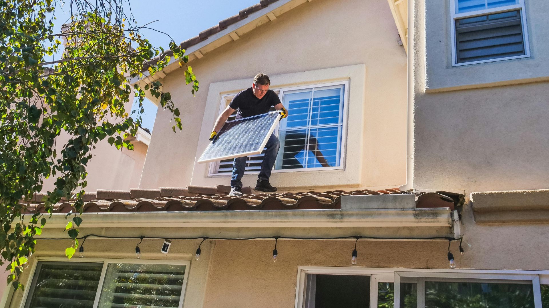 A Man Standing on the Roof Holding a Solar Panel