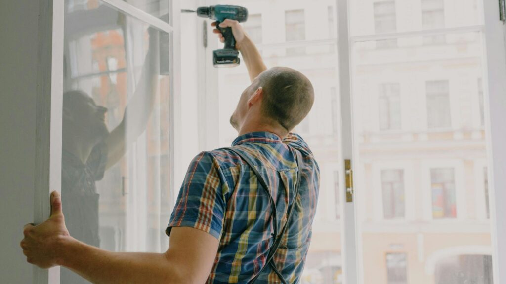 Handyman installing window frame with drill in house