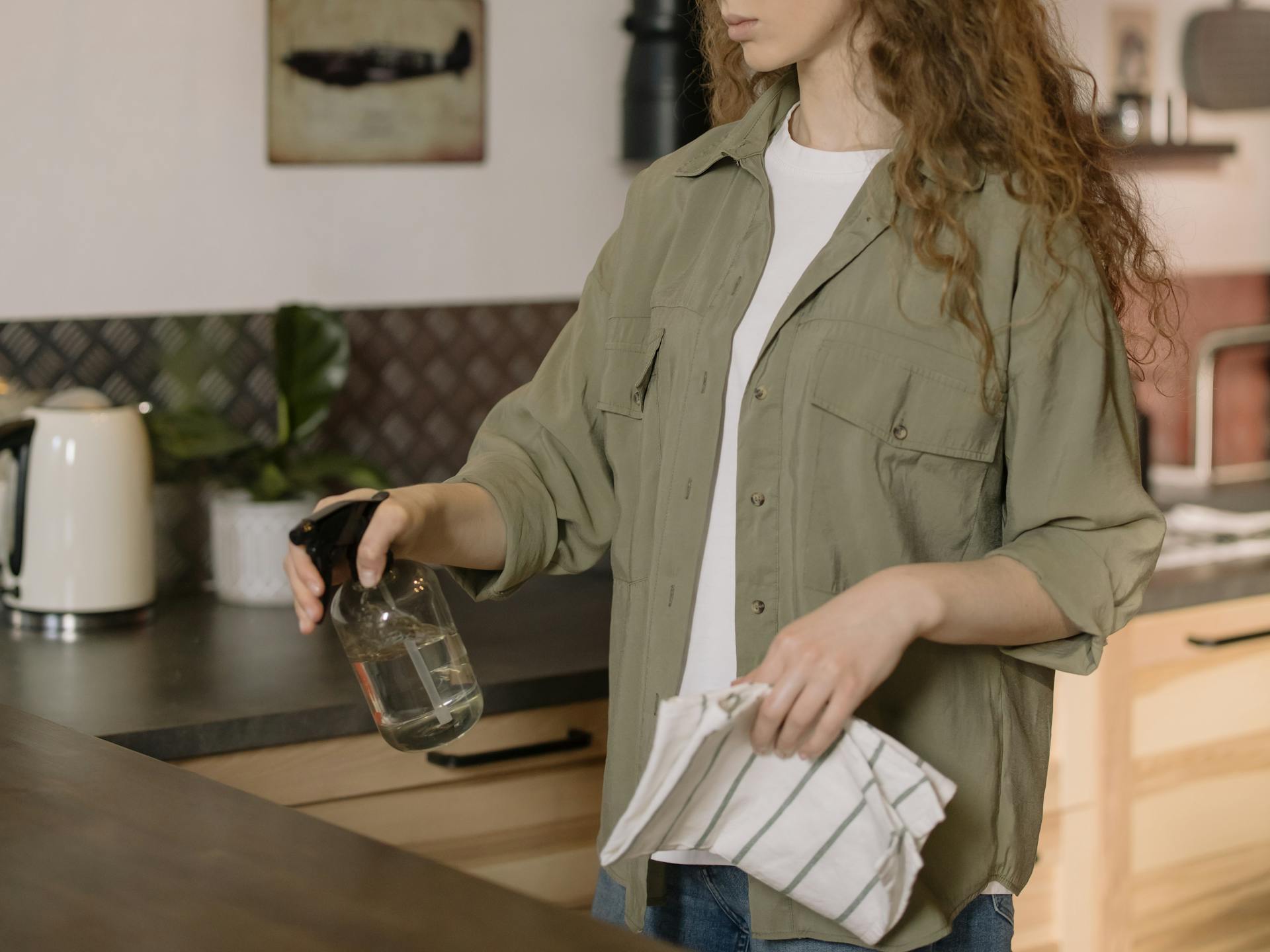 woman in gray cleaning with spray bottle